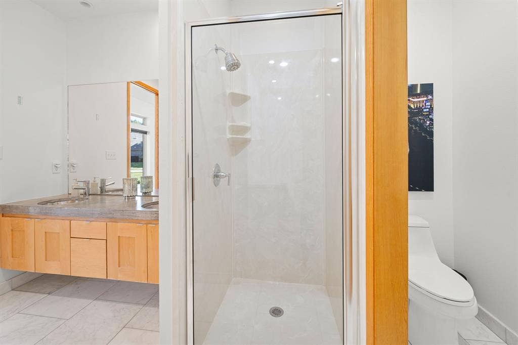 1997 Hollystone Drive, Tyler, TX 75703 Walk-in shower with glass enclosure, floating vanity with dual sinks, stone-finish countertop, and tile flooring