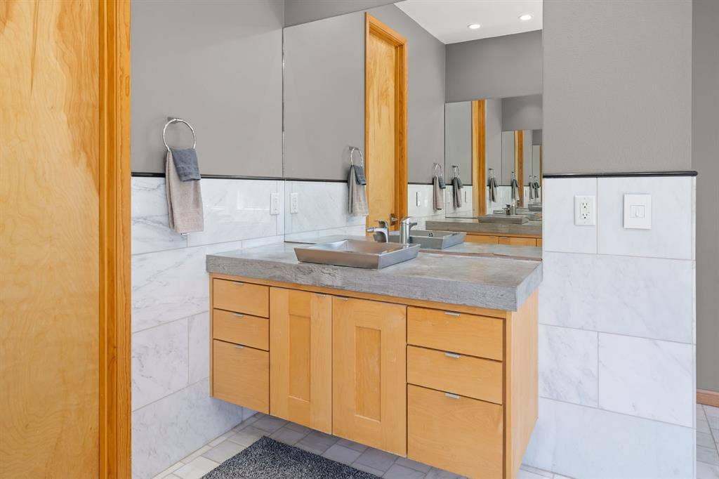 1997 Hollystone Drive, Tyler, TX 75703 Floating wood cabinetry vanity featuring a concrete countertop, square vessel sink, polished chrome faucet, and floor-to-ceiling tile surround