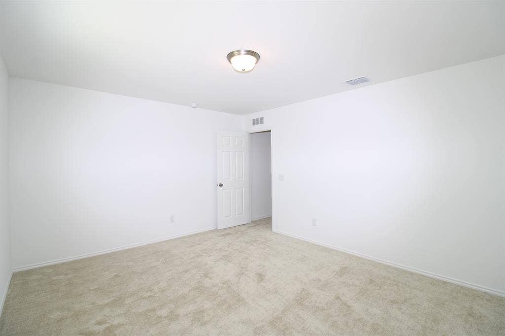 Neutral interior space featuring wall-to-wall carpeting, a six-panel door, and a flush-mount light fixture