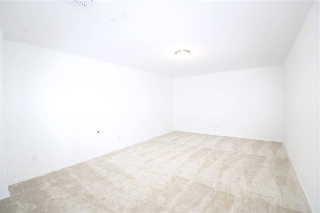 Neutral-toned wall-to-wall carpeting, crisp white walls, and a ceiling-mounted light fixture