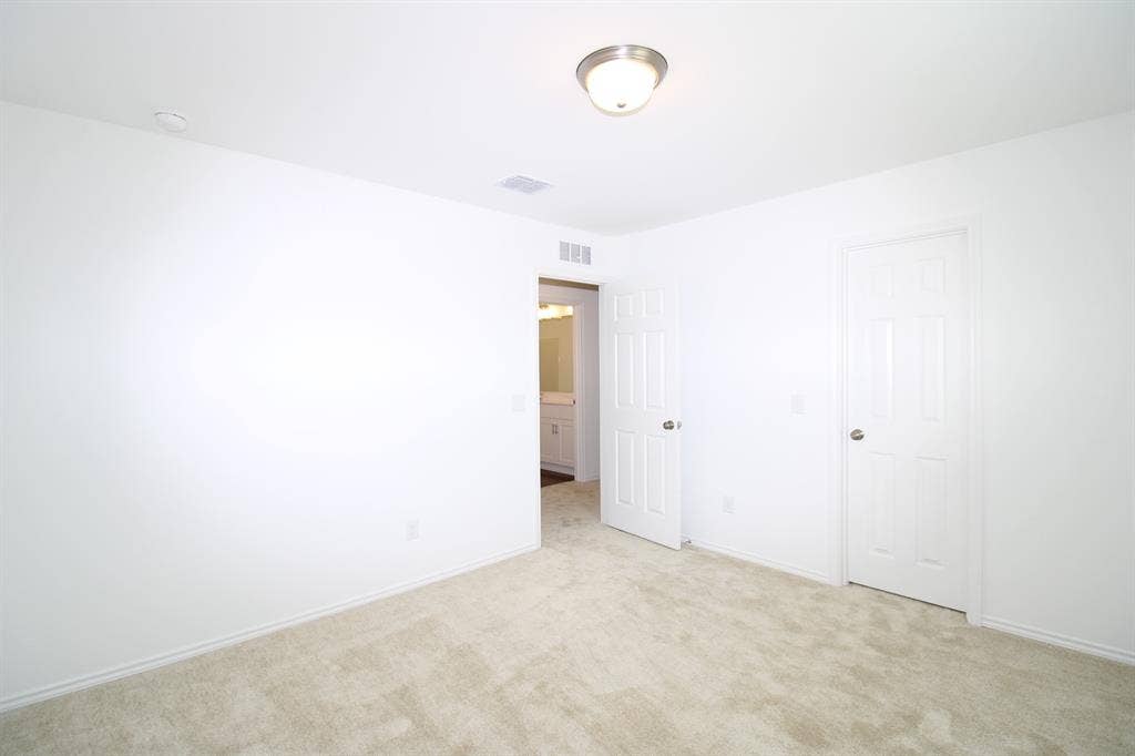 Neutral-toned wall-to-wall carpeting, six-panel interior doors, and a ceiling-mounted flush-mount light fixture