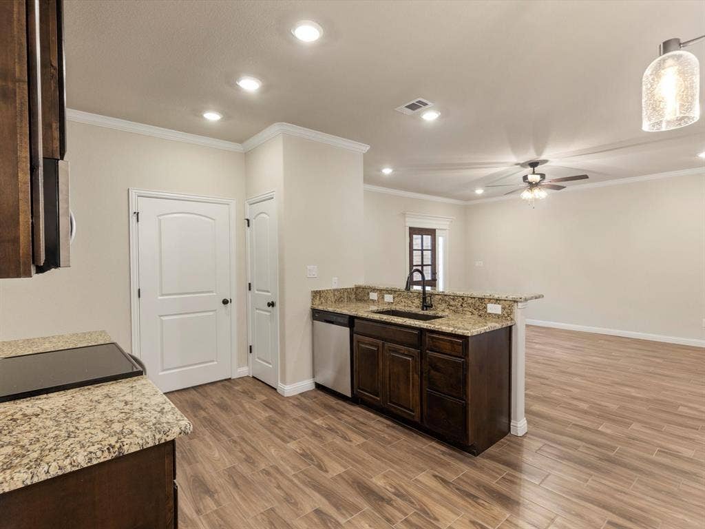 Kitchen featuring dark wood cabinetry, stone countertops, stainless steel dishwasher, wood-finish flooring, and recessed lighting