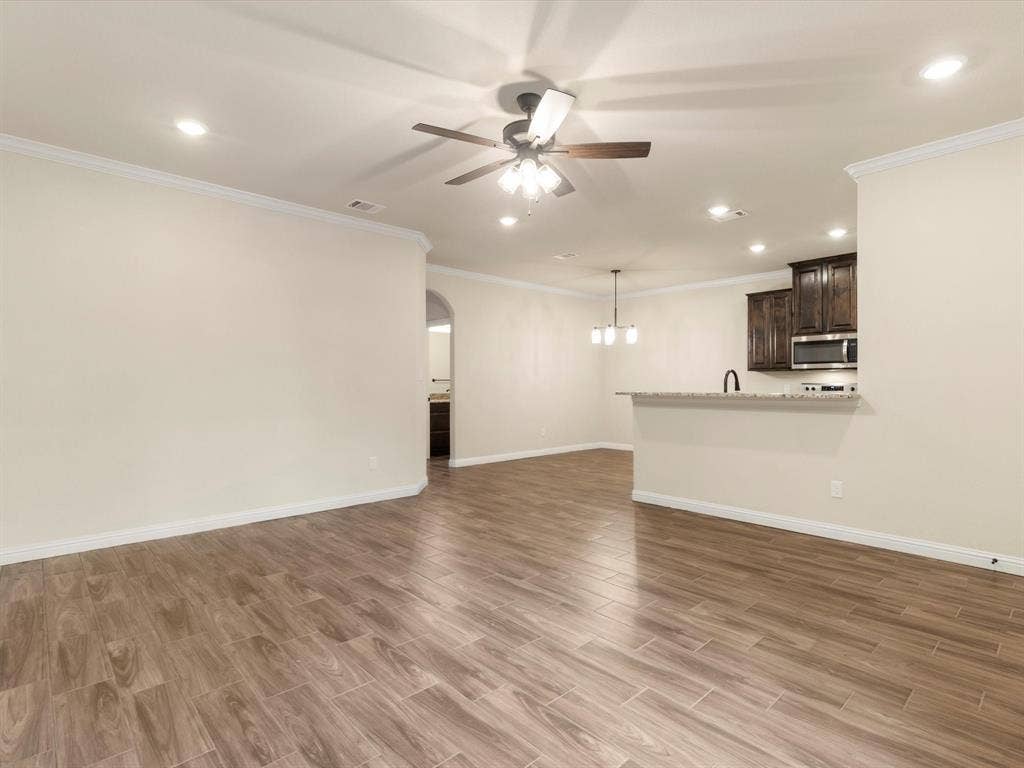 Interior featuring wood-finish tile flooring, recessed lighting, a multi-blade ceiling fan, crown molding, and an arched entryway