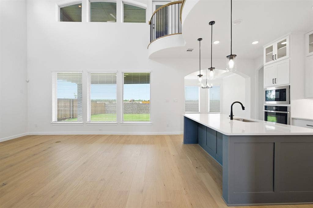 Open-concept living space featuring wood-finish flooring, a two-story ceiling, and a kitchen island with seating