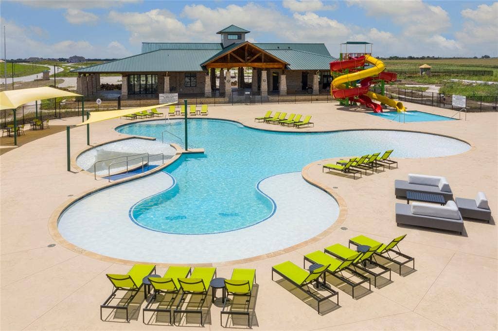 Expansive resort-style swimming pool featuring a recreational water slide, sun shelf areas, and multiple shade structures