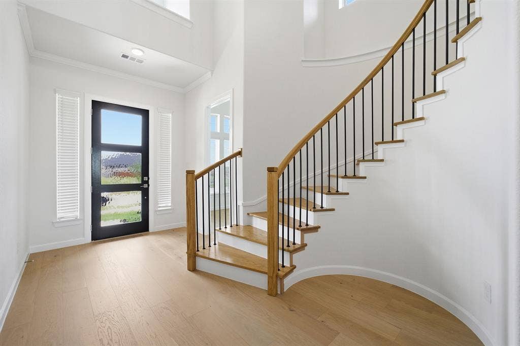 Curved staircase with black iron spindles and wood-finish handrail