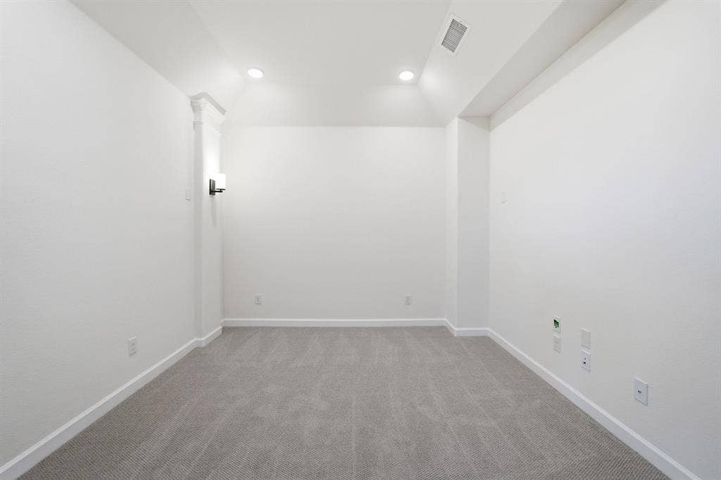 Carpeted room featuring recessed ceiling lighting and a wall sconce