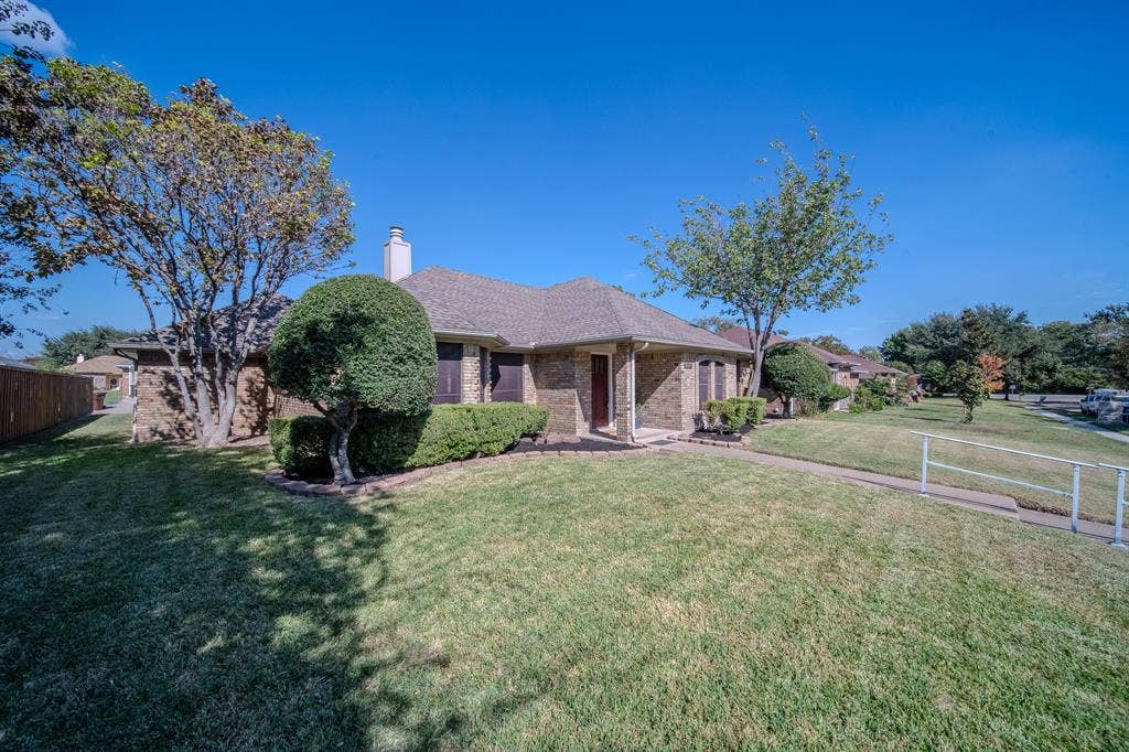 2213 Moore Drive, Plano, TX 75074 Single-story brick exterior featuring a multi-gabled roofline, central masonry chimney, and manicured landscaping
