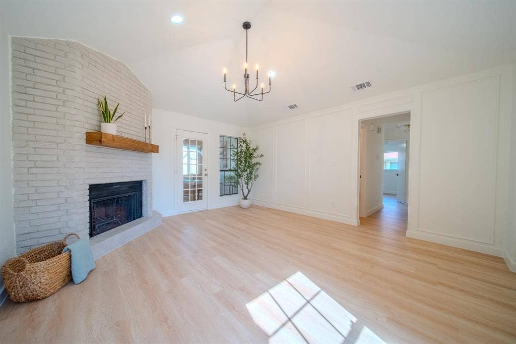 2213 Moore Drive, Plano, TX 75074 Painted brick fireplace with a natural wood mantel, vaulted ceiling, wood-finish flooring, and decorative wall molding