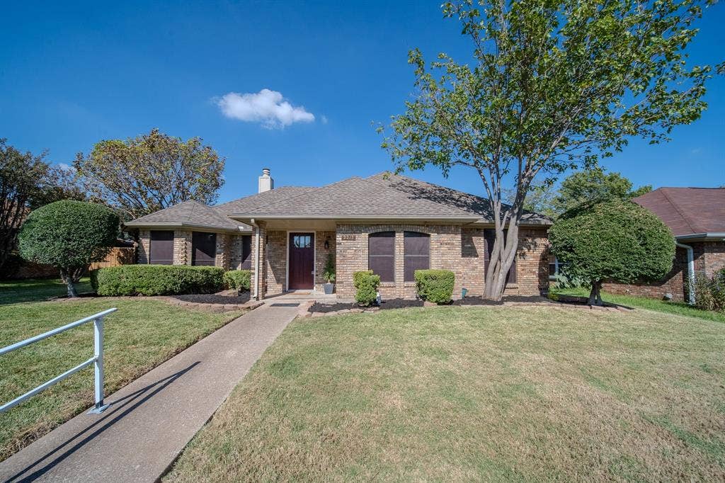 2213 Moore Drive, Plano, TX 75074 Single-story brick exterior featuring a hip roof, covered entryway, concrete walkway, and manicured landscaping