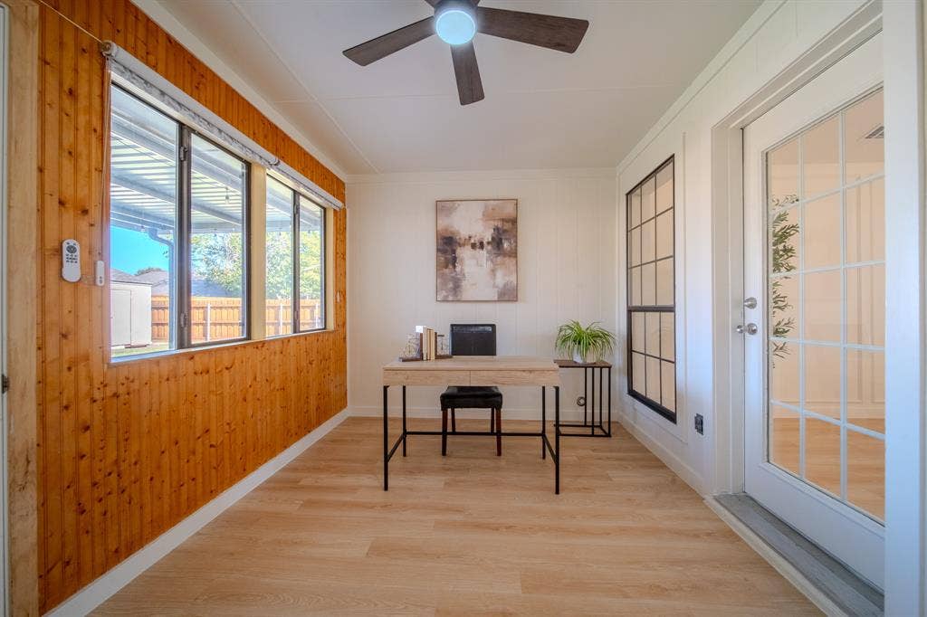 2213 Moore Drive, Plano, TX 75074 Wood-paneled wall accents, wood-finish flooring, full-lite glass exterior door, multi-pane windows, and ceiling-mounted fan