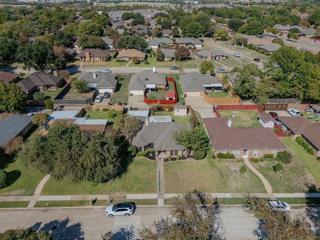 2213 Moore Drive, Plano, TX 75074 Aerial perspective featuring a single-story residence with a multi-gabled roof, brick exterior, expansive front lawn, and mature trees