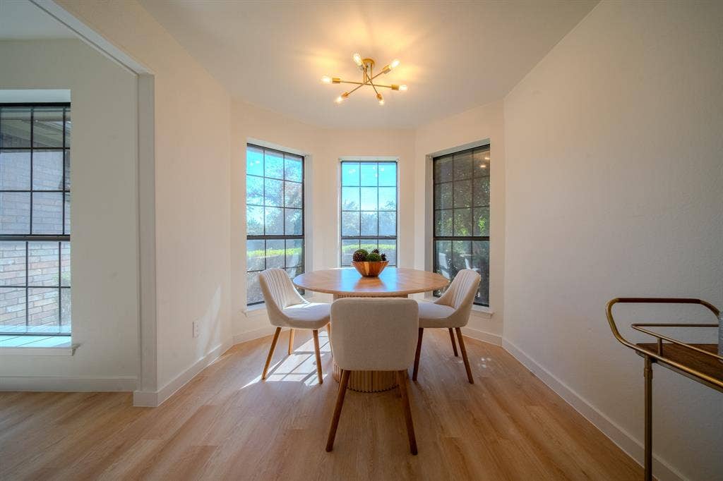2213 Moore Drive, Plano, TX 75074 Bay window area featuring multi-pane windows, wood-finish flooring, and a modern multi-arm brass light fixture