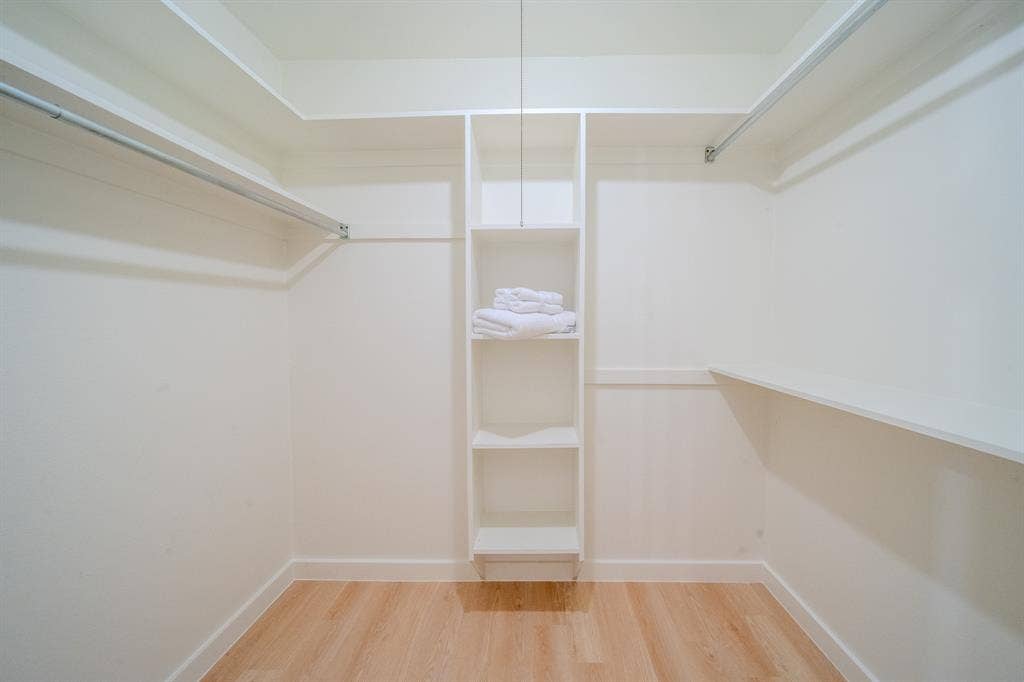 2213 Moore Drive, Plano, TX 75074 Walk-in closet featuring white built-in shelving, wooden rods, and wood-finish flooring