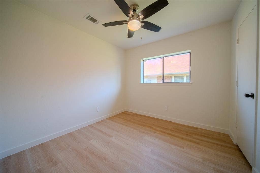 2213 Moore Drive, Plano, TX 75074 Neutral-toned interior room featuring wood-finish flooring, a ceiling fan with integrated lighting, and a single-pane window