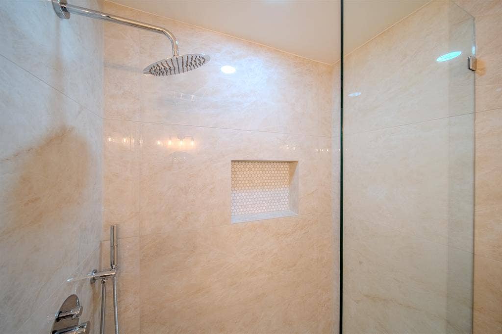 2213 Moore Drive, Plano, TX 75074 Walk-in shower featuring large-format tile wall surround, glass partition, rainfall showerhead, integrated tiled niche with mosaic accent, and polished chrome fixtures