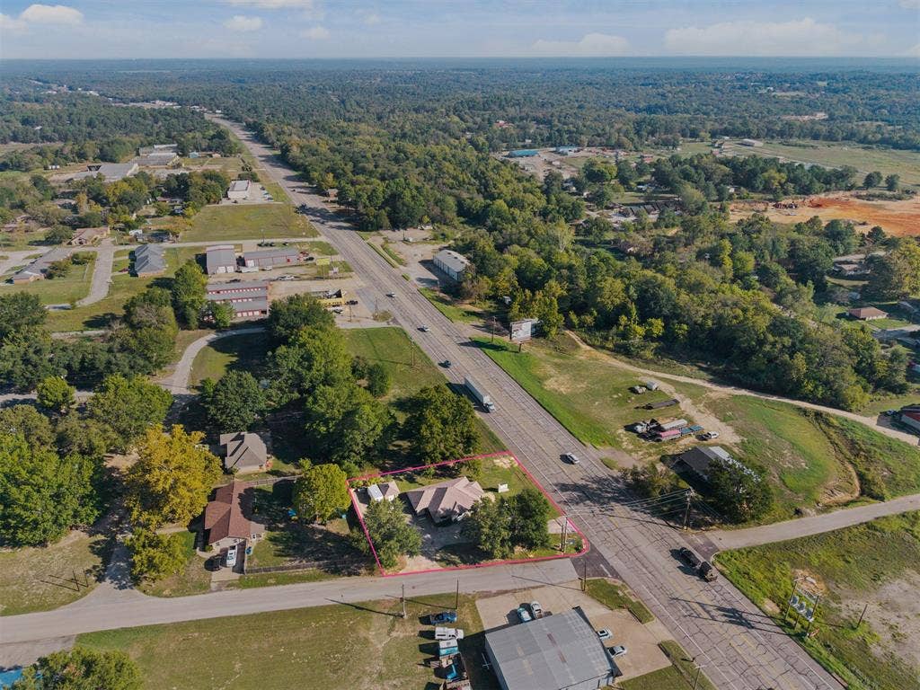 700 N Main Street, Lindale, TX 75771 Aerial perspective of a property featuring a multi-pitched roofline, asphalt shingle roofing, and mature perimeter trees situated on a corner lot