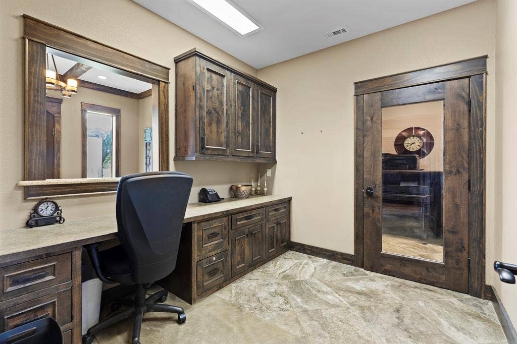 700 N Main Street, Lindale, TX 75771 Custom wood cabinetry with integrated desk space, stone-surfaced countertops, framed wall mirror, glass-paneled wood door, and tile flooring