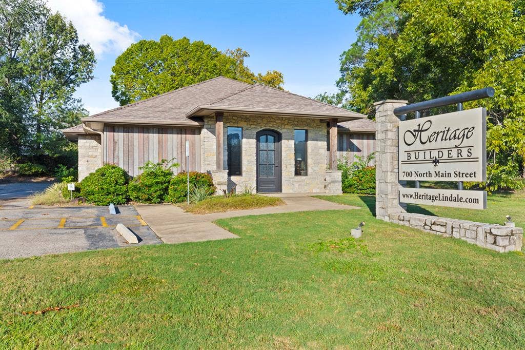 700 N Main Street, Lindale, TX 75771 Exterior featuring a stone and wood-paneled facade, a hip roof with asphalt shingles, an arched entryway, and integrated masonry signage