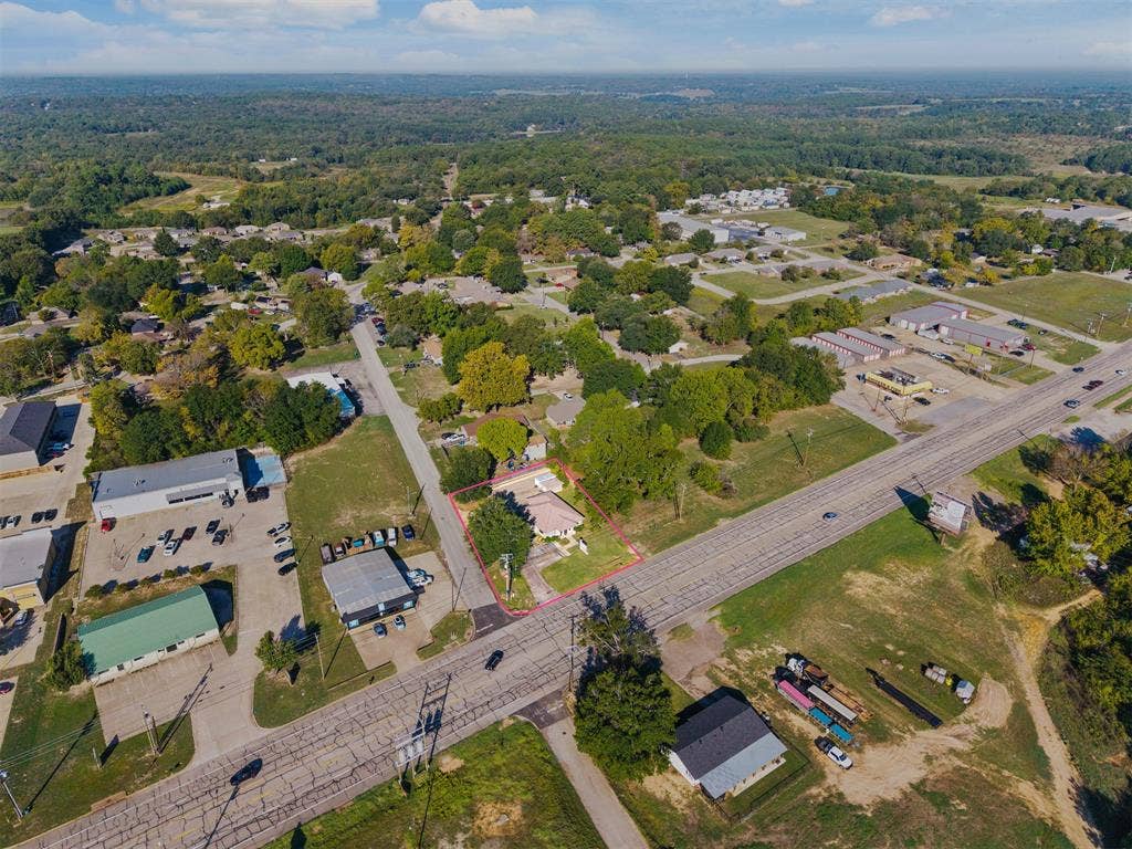 700 N Main Street, Lindale, TX 75771 Aerial perspective showcasing a single-story residence situated on a landscaped lot with mature trees and paved driveway access