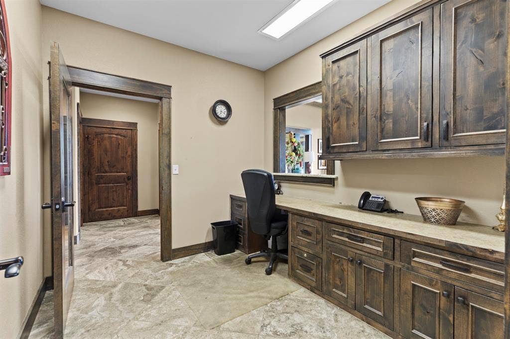 700 N Main Street, Lindale, TX 75771 Built-in stained wood cabinetry with upper and lower storage, stone-surface desktop, tile flooring, and matching wood trim and door casing