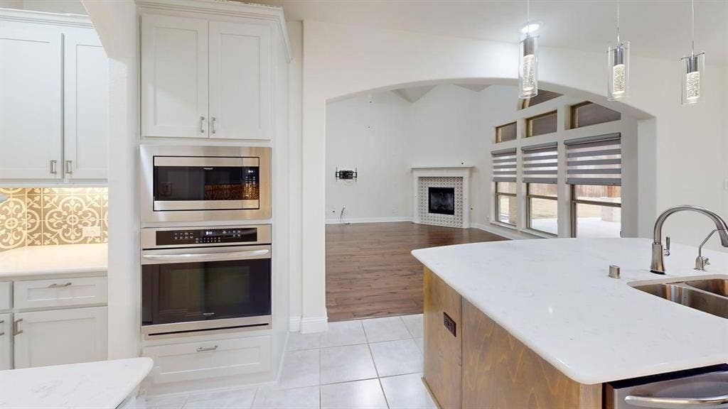 14518 Shady Grove Lane, Frisco, TX 75035 Kitchen featuring white cabinetry, stainless steel double wall ovens, a center island with a stone-composite countertop, and a decorative tile backsplash