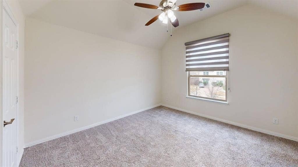 14518 Shady Grove Lane, Frisco, TX 75035 Vaulted ceiling featuring a central multi-blade ceiling fan with integrated lighting, neutral wall tones, carpeted flooring, and a window with installed roller shade