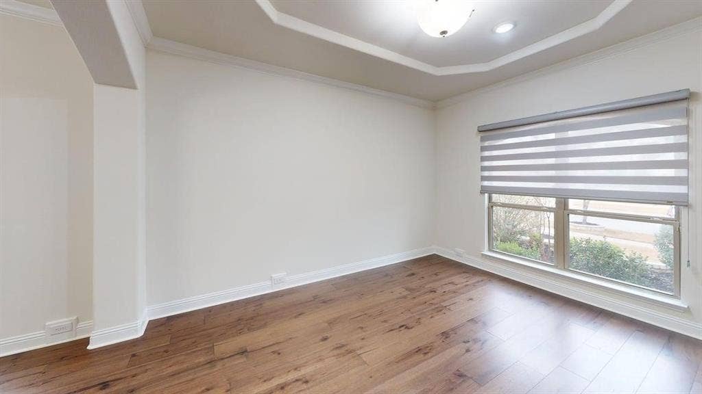14518 Shady Grove Lane, Frisco, TX 75035 Room featuring tray ceilings, wood-finish flooring, a neutral color palette, and a large window with installed roller shades