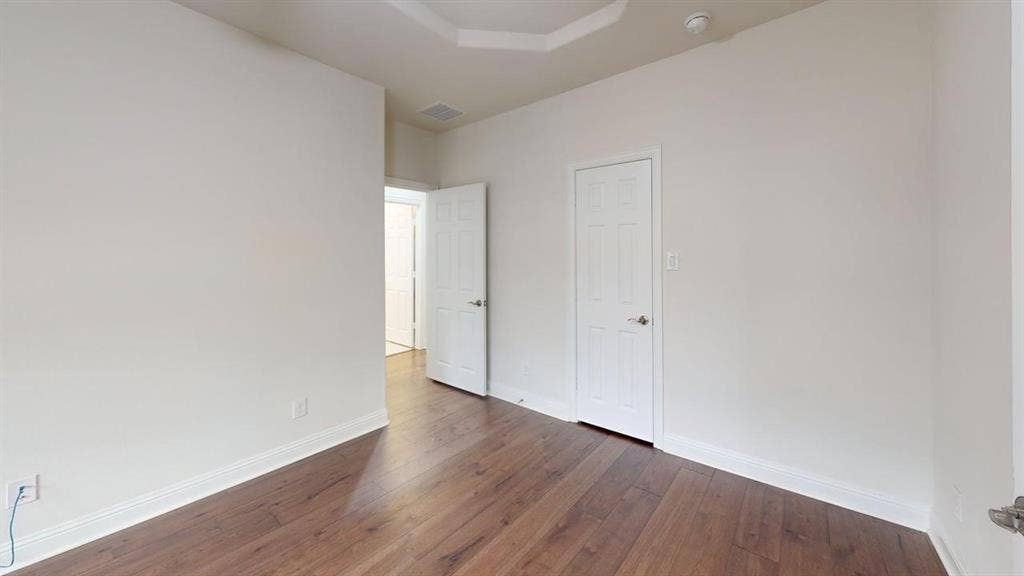 14518 Shady Grove Lane, Frisco, TX 75035 Interior room featuring wood-finish flooring, a tray ceiling, and dual interior doors