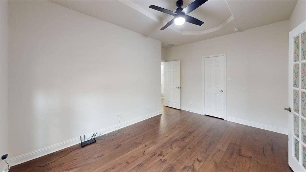 14518 Shady Grove Lane, Frisco, TX 75035 Room featuring wood-finish flooring, a tray ceiling, and a ceiling-mounted light fixture with fan