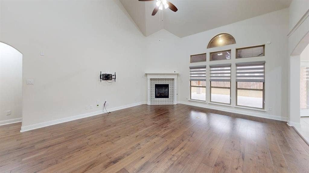 14518 Shady Grove Lane, Frisco, TX 75035 Vaulted ceilings featuring a central fan, wood-finish flooring, and a fireplace with a tiled surround