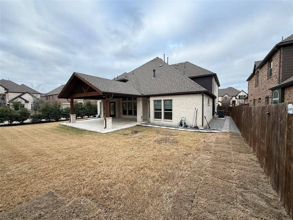 14518 Shady Grove Lane, Frisco, TX 75035 Rear exterior featuring a covered patio with timber framing, stone-clad support pillars, masonry facade, and wood-panel privacy fencing