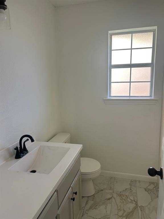 1114 Idlewood Drive, Waco, TX 76705 Bathroom featuring a vanity with a white countertop, rectangular integrated sink, and matte black faucet, accompanied by light-toned stone-finish tile flooring and a multi-pane window