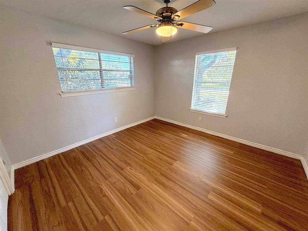 2701 Northcrest Drive, Plano, TX 75075 Room featuring wood-finish flooring, dual windows with horizontal blinds, and a central ceiling fan with integrated lighting