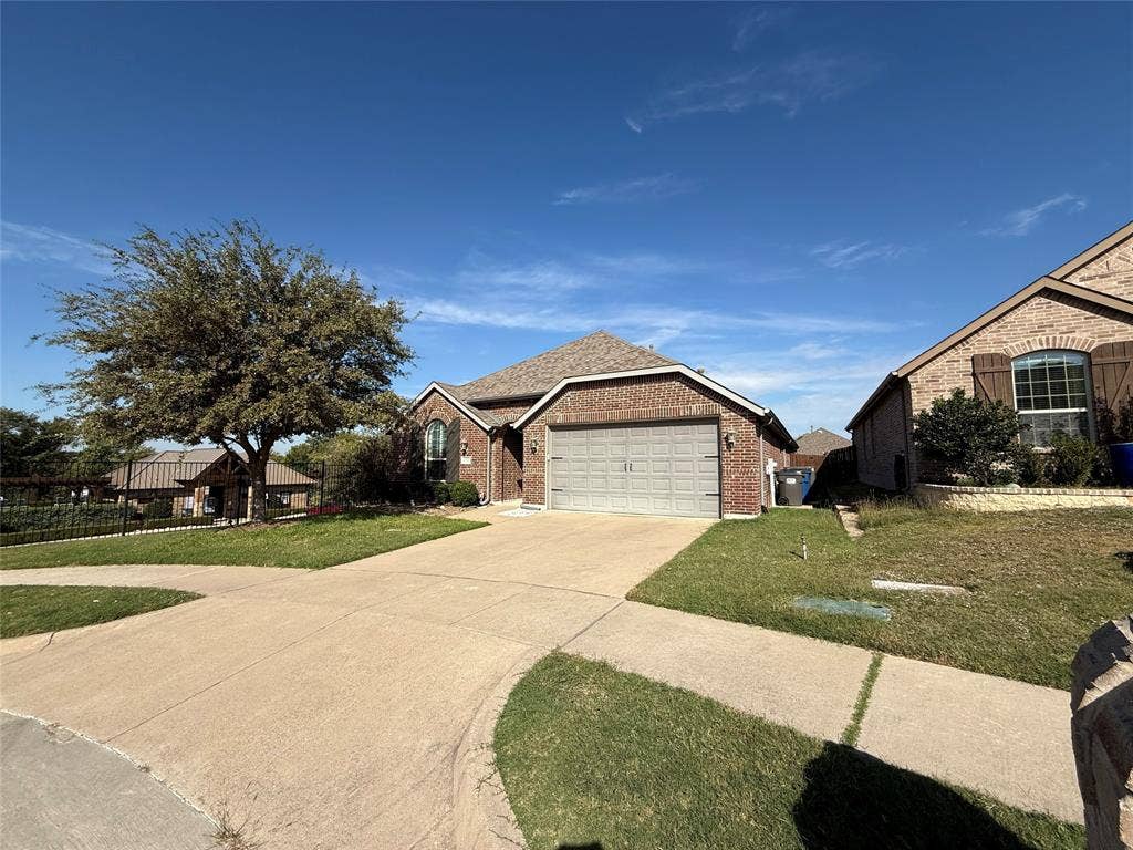 1702 Sagebrush Trail, Wylie, TX 75098 Brick exterior residence featuring a front-facing attached two-car garage, arched window accents, and a concrete driveway