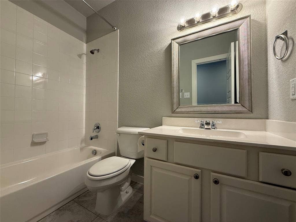 1702 Sagebrush Trail, Wylie, TX 75098 Bathroom featuring a white vanity cabinet with an integrated sink, framed wall mirror, multi-bulb vanity light, and a tile-surround shower and tub combination