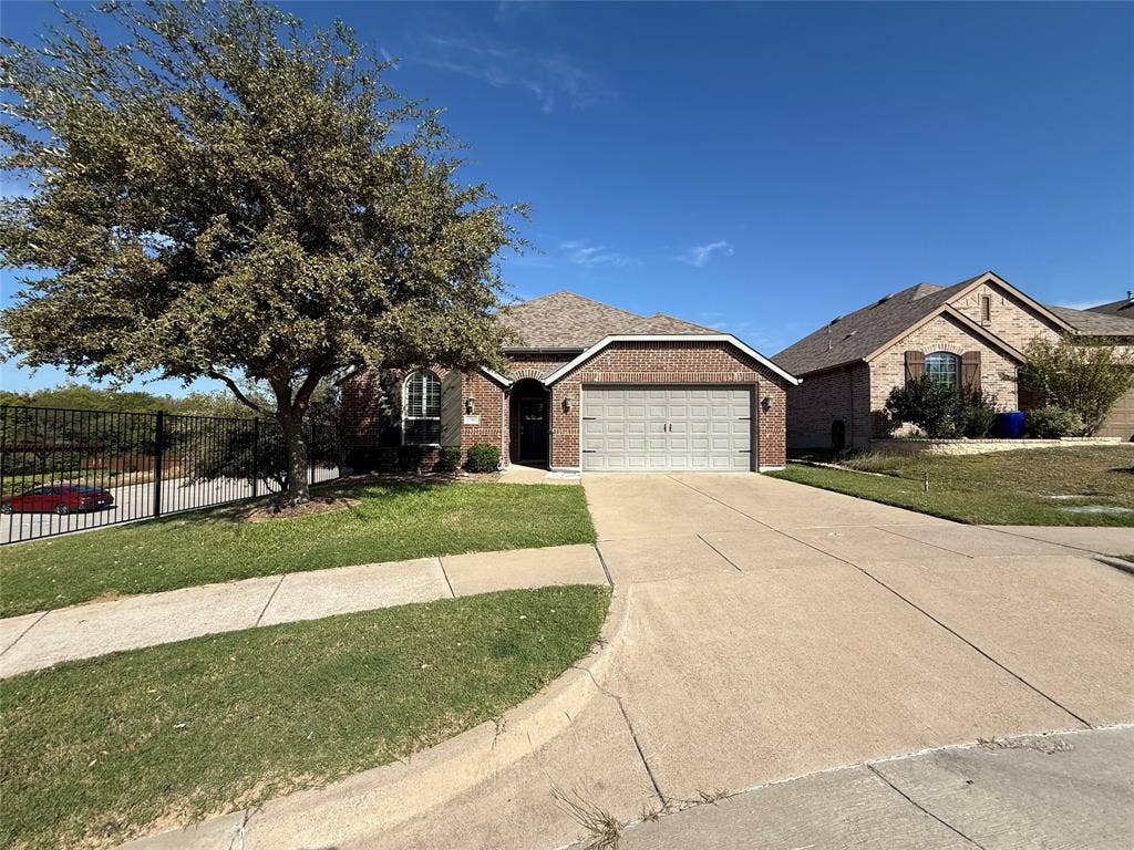 1702 Sagebrush Trail, Wylie, TX 75098 Brick exterior featuring a gabled roofline, front-facing two-car garage, concrete driveway, and mature landscaping