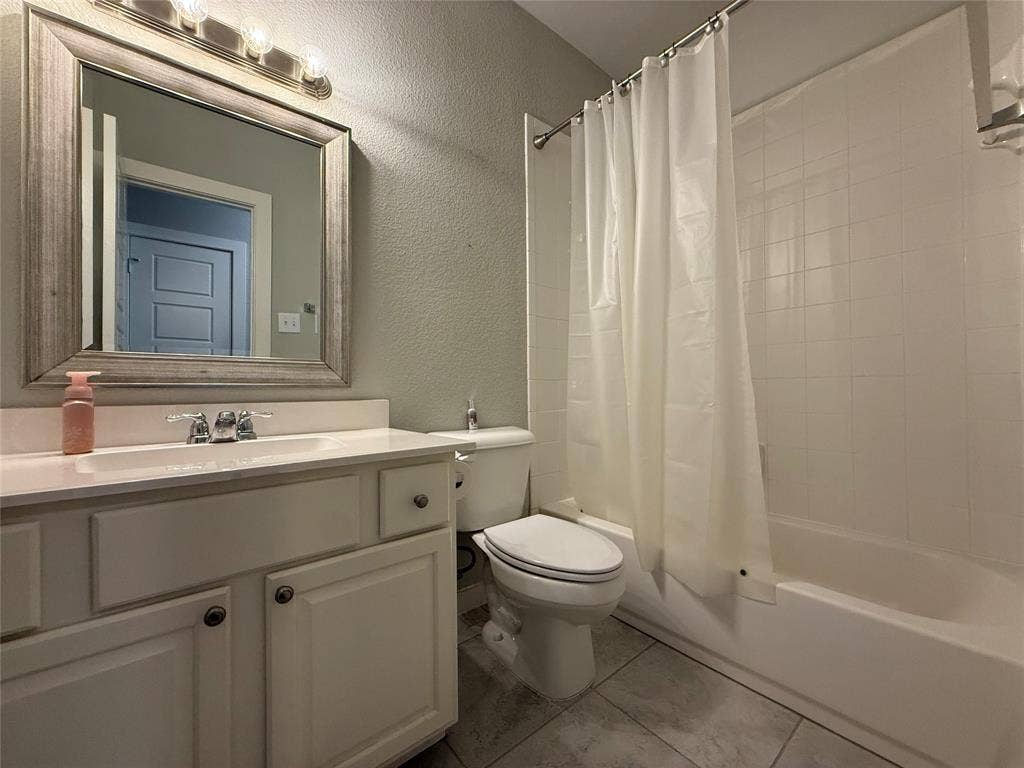 1702 Sagebrush Trail, Wylie, TX 75098 Bathroom featuring a white vanity cabinet with an integrated sink, a framed vanity mirror with four-light fixture, tile flooring, and a shower-tub combination with white wall tile