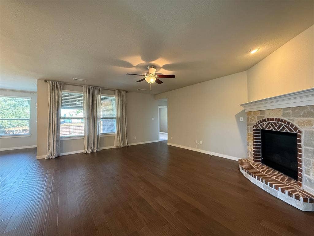 1702 Sagebrush Trail, Wylie, TX 75098 Open living space featuring wood-finish flooring, recessed lighting, ceiling fan, and a fireplace with brick masonry and stone detailing