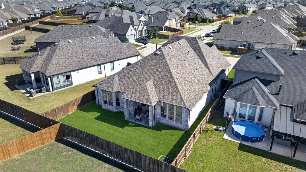 1103 Walford Drive, Forney, TX 75126 Aerial view of residential property featuring a brick and stone exterior, a rear-covered patio, and a fully fenced backyard with a grass lawn