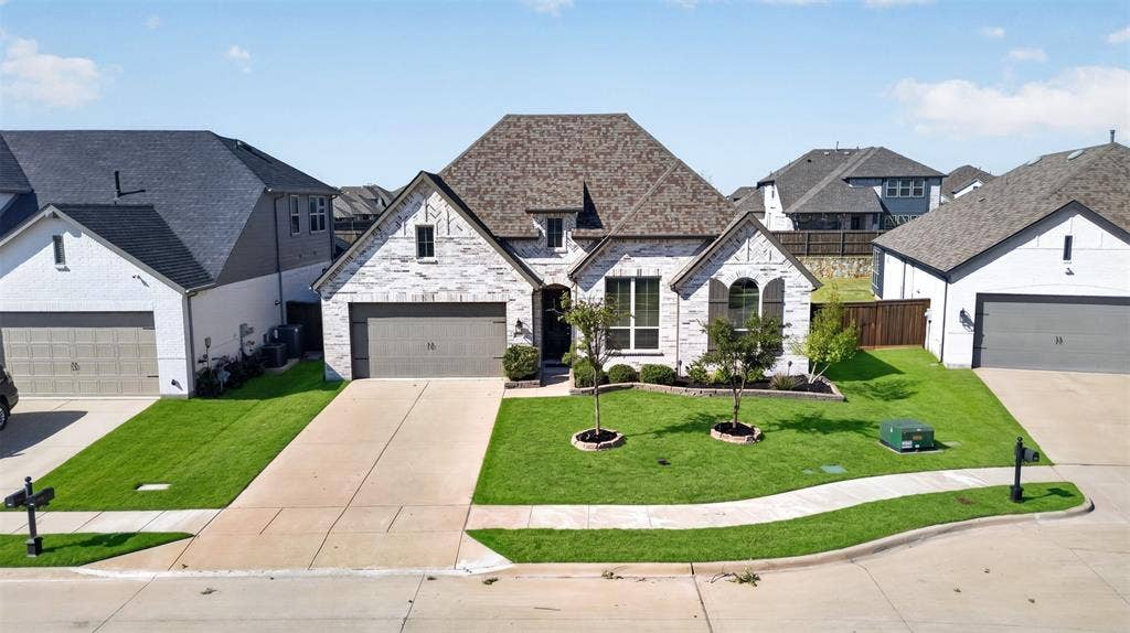 1103 Walford Drive, Forney, TX 75126 Stone and masonry exterior featuring a multi-gabled roofline, an attached two-car garage, and manicured landscaping