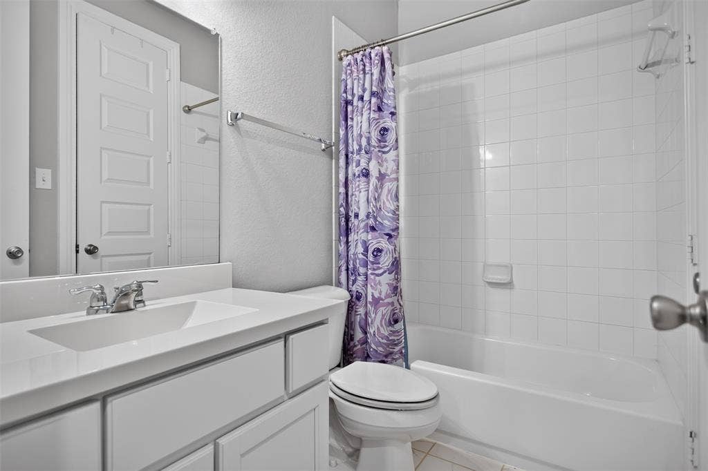 1103 Walford Drive, Forney, TX 75126 Bathroom featuring a white vanity cabinet, solid-surface countertop with an integrated sink, polished chrome faucet, and a shower-tub combination with white wall tile