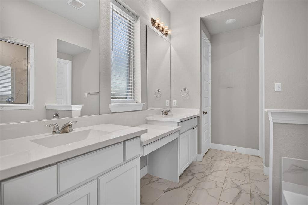 1103 Walford Drive, Forney, TX 75126 Dual vanity with light-toned cabinetry, solid surface countertops, integrated sinks, chrome fixtures, and large plate-glass mirrors