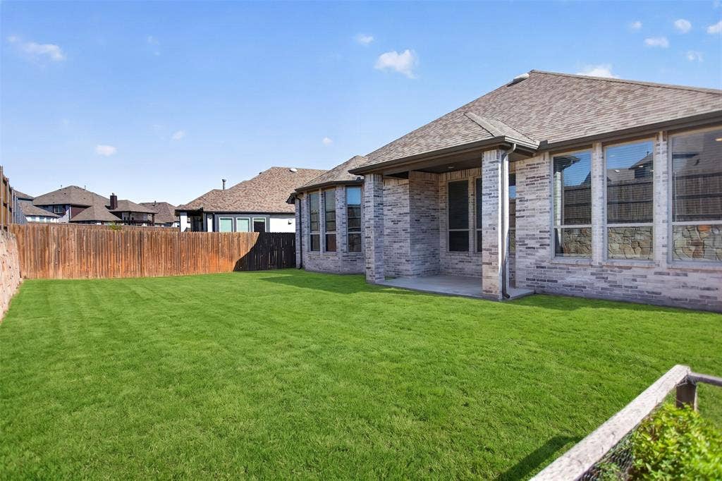 1103 Walford Drive, Forney, TX 75126 Brick exterior siding, covered concrete patio, and fenced backyard with a grass lawn