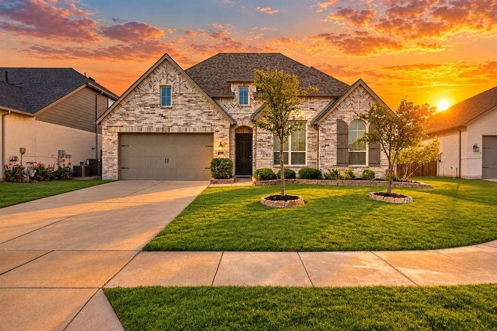1103 Walford Drive, Forney, TX 75126 Multi-gabled brick and masonry exterior with an attached two-car garage, manicured lawn, and stone-bordered landscaping