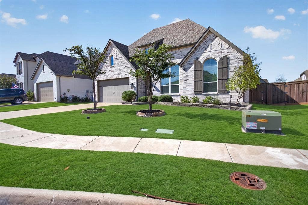 1103 Walford Drive, Forney, TX 75126 Stone and brick facade featuring arched windows, decorative wooden shutters, a multi-gabled roofline, and a paved driveway