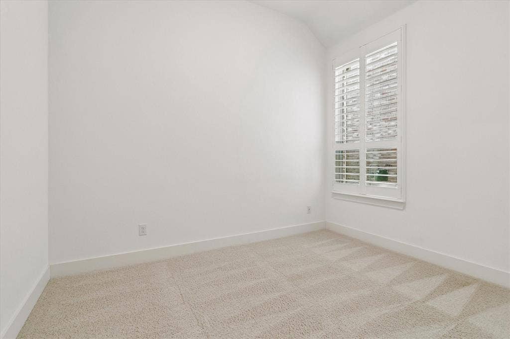 Room featuring neutral carpeting, vaulted ceiling, and white plantation shutters