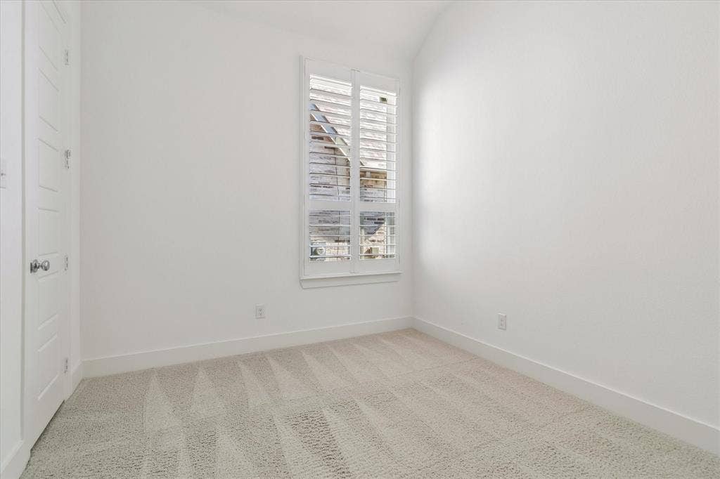 Interior room featuring neutral wall-to-wall carpeting, white paneled doors, and a single window with white plantation shutters