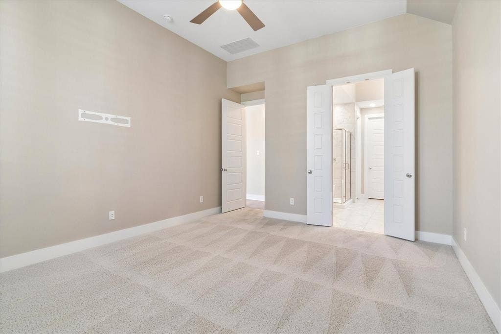 Neutral-toned room featuring high vaulted ceilings, wall-to-wall carpeting, a ceiling fan with integrated lighting, and white paneled doors