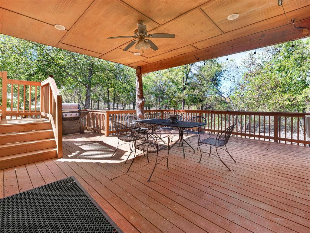 Expansive wood deck featuring a covered area with paneled ceiling, recessed lighting, and a ceiling fan, enclosed by wooden railings